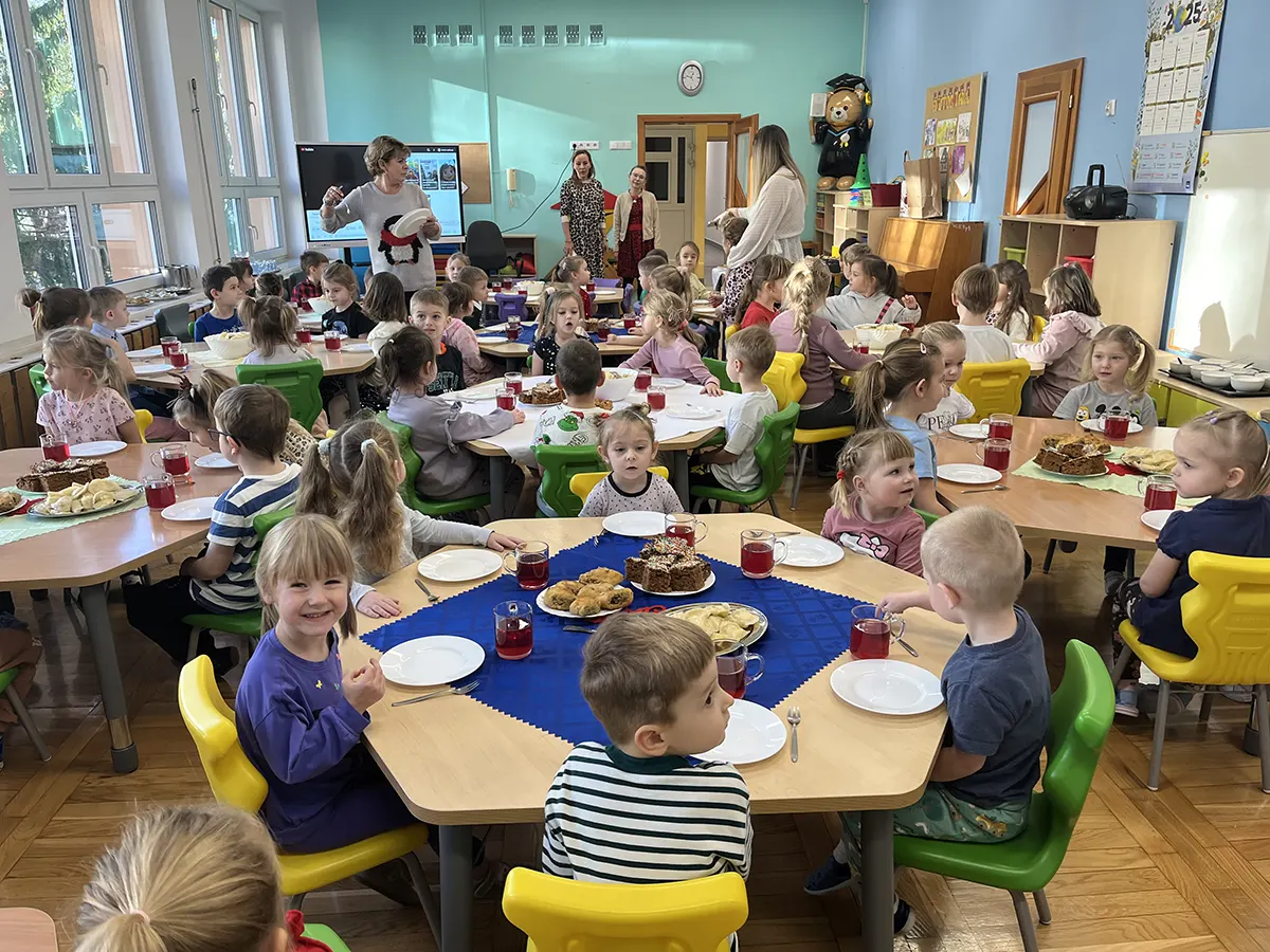  Dzieci siedzą przy stołac...